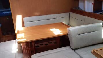 Un intérieur compact avec une table en bois, des sièges rembourrés et une étagère intégrée.