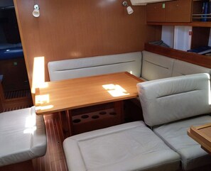 A compact interior with a wooden table, cushioned seating, and a built-in shelf.