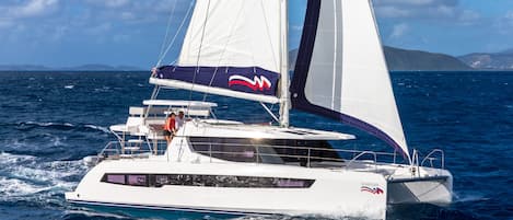 A white yacht with a cabin and a sail, sailing on the water.