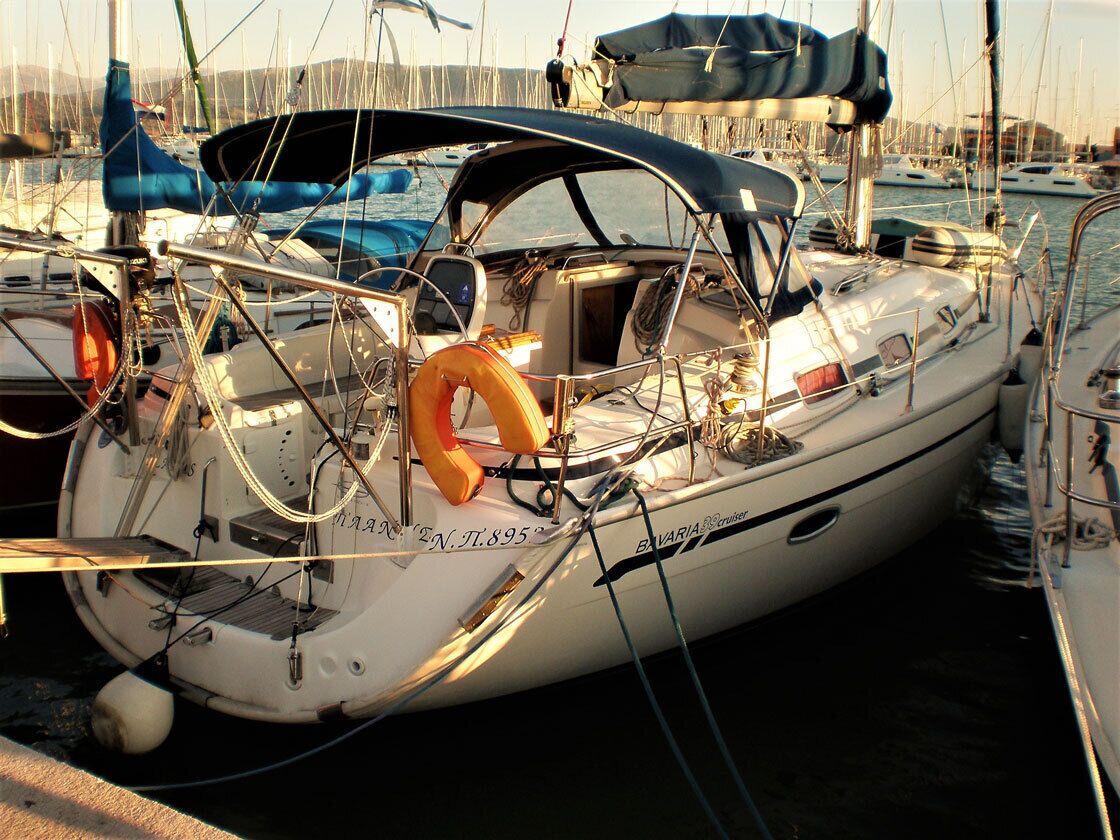 A sailboat docked at a marina with visible rigging and a lifebuoy.