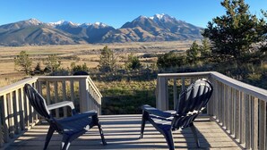 A deck with two Adirondack chairs facing a mountainous landscape.