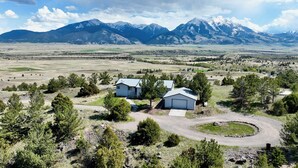 A rural property with two detached houses, a circular driveway, and a mountainous backdrop.