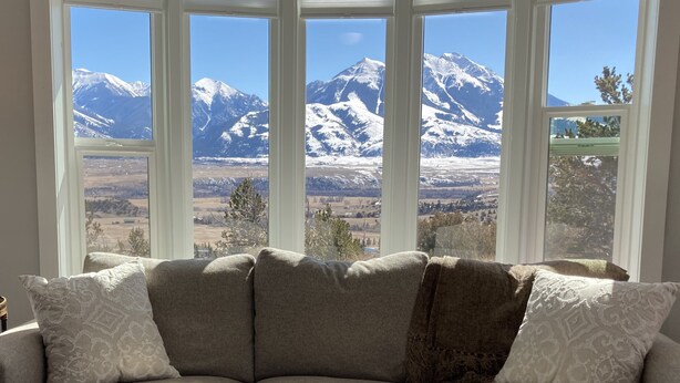 A room with a large bay window offering a view of snow-capped mountains.
