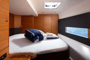 Ein modernes Schlafzimmer mit Bett, Fenster mit Meerblick, Oberlicht und Holzvertäfelung.