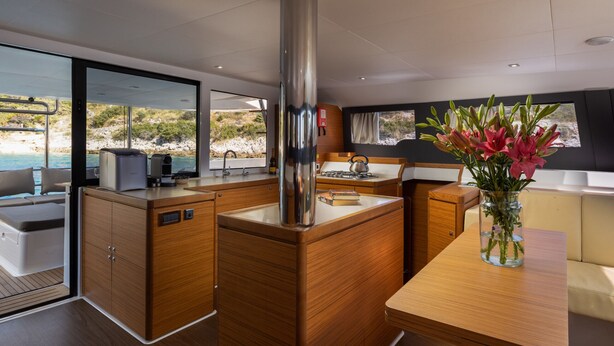 Een moderne keuken met houten kastjes, een rvs fornuis en uitzicht op zee.