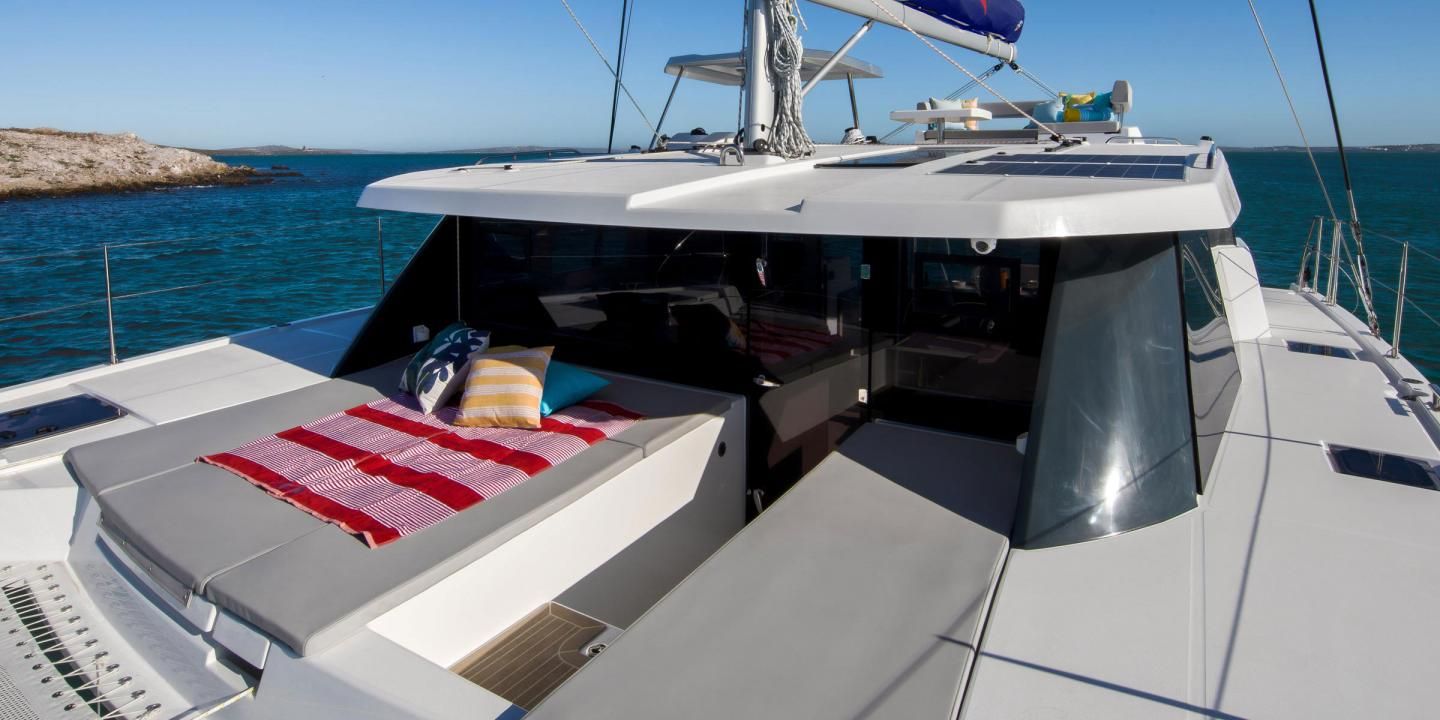 Le pont d’un yacht, avec un bain de soleil, une petite table et une vue sur la mer.