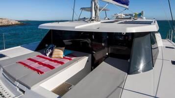 A yacht's deck with a sunbed, a small table, and a view of the sea.