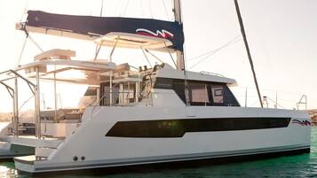 Un grand yacht blanc doté d’un pont partiellement couvert et arborant un logo sur le côté.
