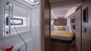 Un intérieur compact et bien éclairé, comprenant un lit, une fenêtre et un espace douche.