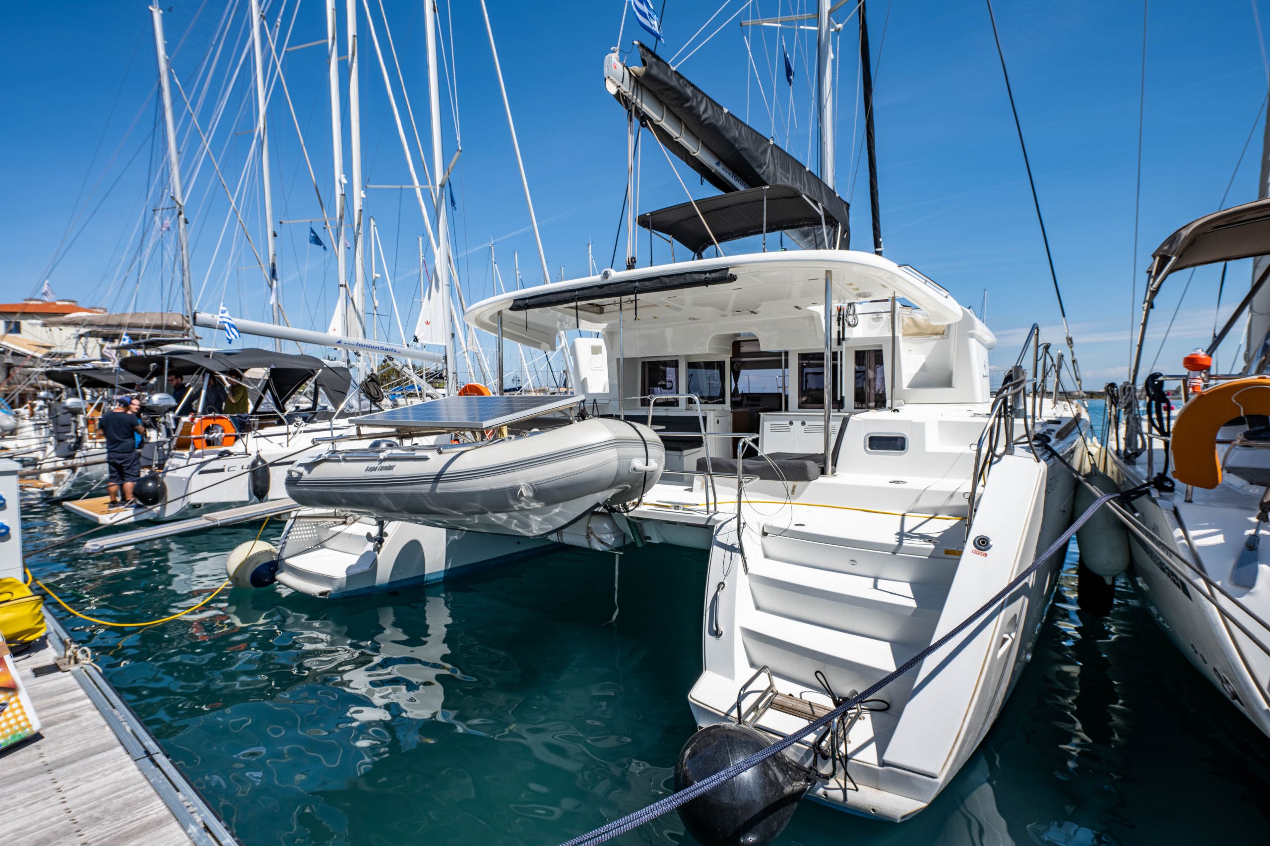 A marina with multiple boats docked, including a white yacht with a covered deck and a smaller inflatable boat.