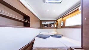 Ein kompakter, gut beleuchteter Innenraum mit einem Bett, Ablageflächen und einem Fenster.