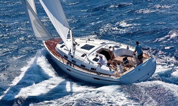 A sailboat with a cabin, deck, and a person steering.