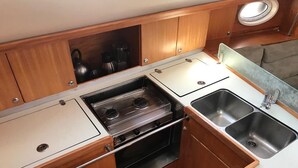 A compact kitchen with a gas stove, two sinks, wooden cabinets, and a small countertop.