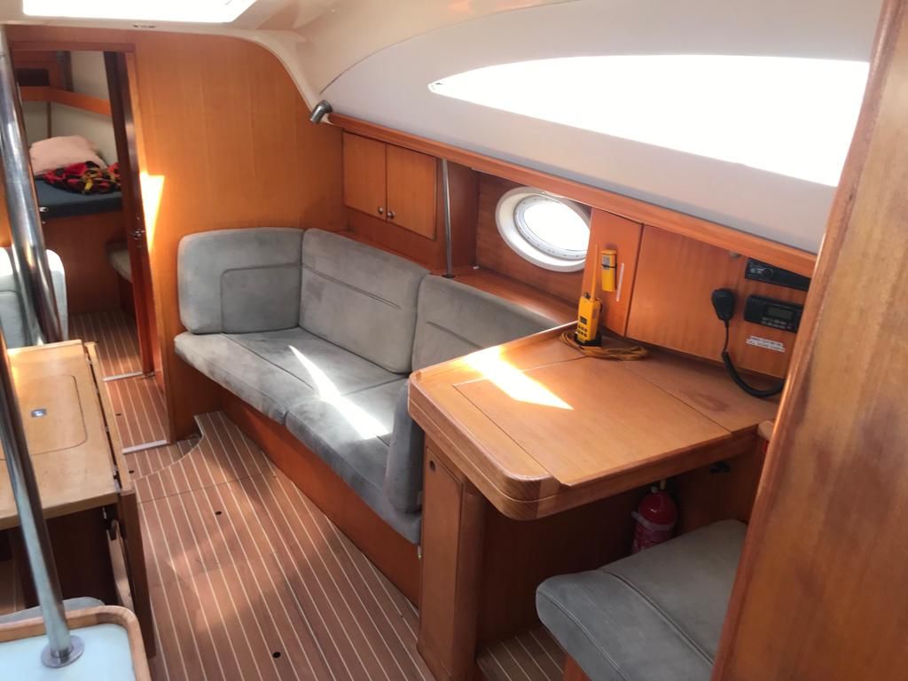 A compact interior with a cushioned seating area, a small table, and a window.