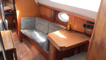 A compact interior with a cushioned seating area, a small table, and a window.