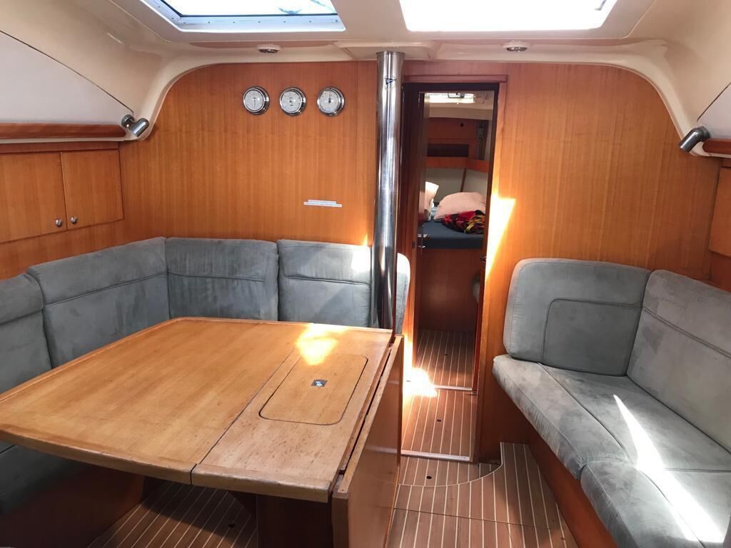 A compact interior with a central table, two seating areas, a skylight, and a door leading to another room.