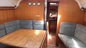 A compact interior with a central table, two seating areas, a skylight, and a door leading to another room.