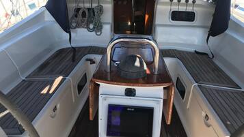 A boat's interior with a steering wheel, a B&G navigation screen, and various ropes and equipment.