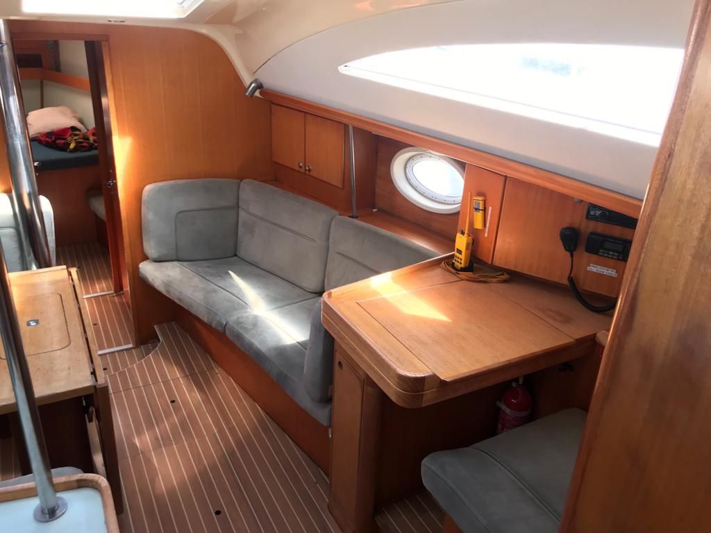 A compact interior with a cushioned seating area, a small table, and a window.