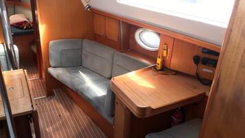 A compact interior with a cushioned seating area, a small table, and a window.