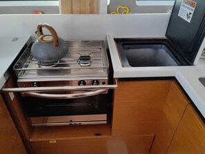 Una cocina compacta con estufa de acero inoxidable, un lavamanos y armarios de madera.