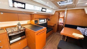 A compact galley with a stove, oven, and a small seating area with a table. - Sun-Kissed Sailing Adventure in Split, Croatia (Split)