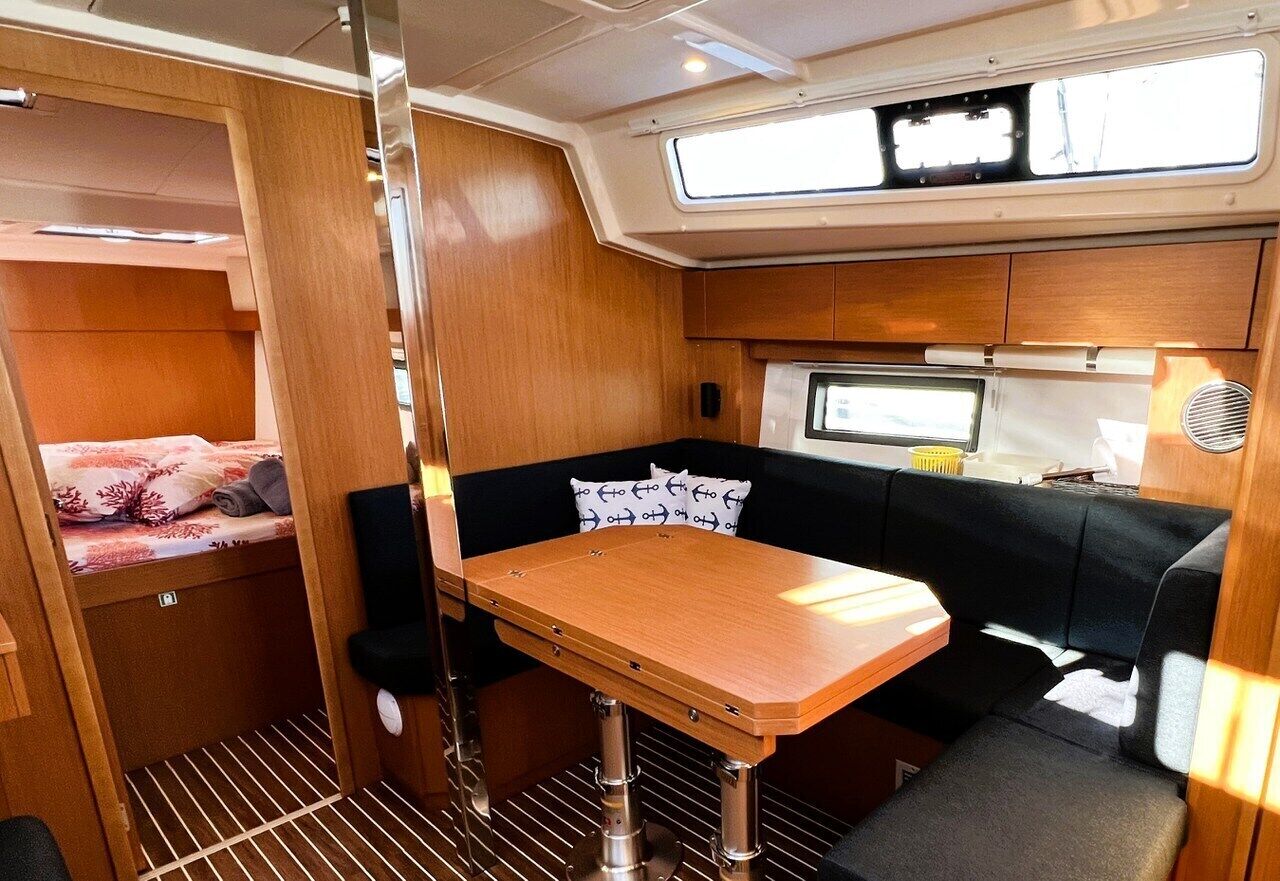 A compact interior with a bunk bed, a small dining table, and a seating area with cushions.