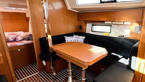 A compact interior with a bunk bed, a small dining table, and a seating area with cushions. - Sun-Kissed Sailing Adventure in Split, Croatia (Split)