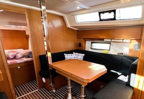 A compact interior with a bunk bed, a small dining table, and a seating area with cushions. - Sun-Kissed Sailing Adventure in Split, Croatia (Split)