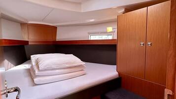 A compact cabin with a skylight, a bed with white linens, a small sink, and wooden cabinetry.