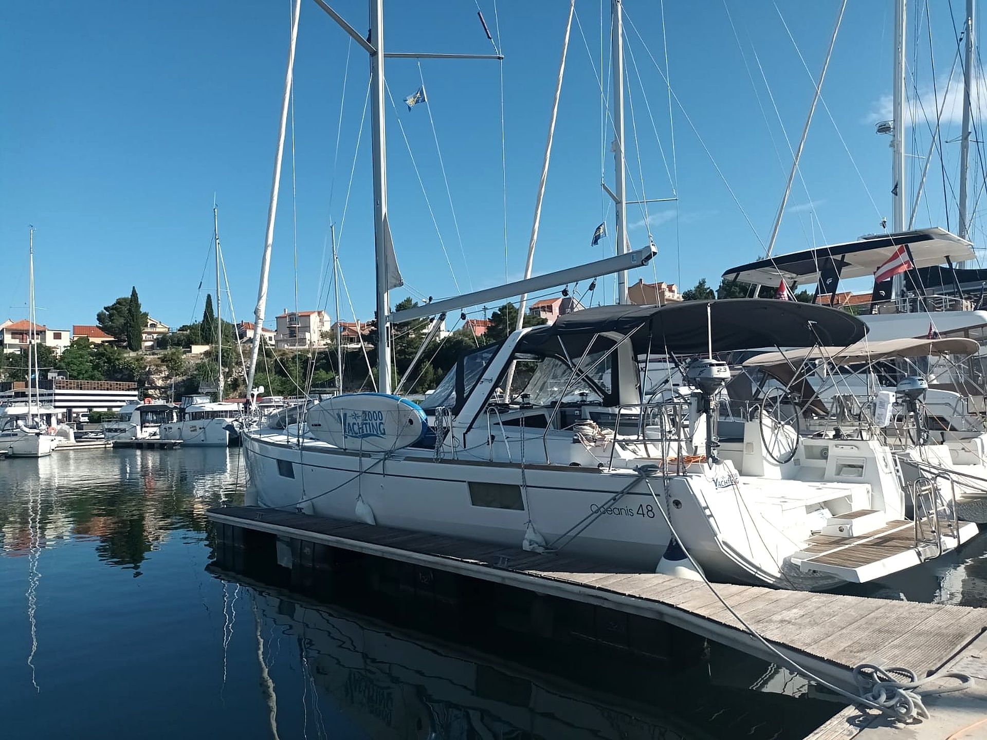 A marina with several sailboats docked, featuring a wooden deck and a cabin with a covered area.