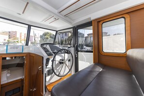 A boat interior with a steering wheel, a wooden cabinet, and a view of the outside. - Sun-Kissed Sailing Adventure in Zadar, Croatia (Zadar)
