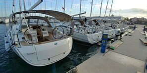 Marina con varios veleros amarrados, que incluye una cubierta de madera y un panel de control.