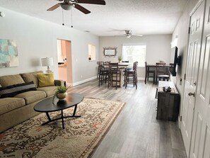 A living room with a sofa, coffee table, and a dining area with chairs and a table.