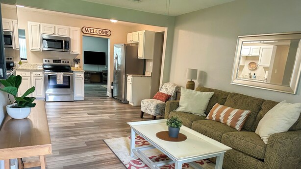 A modern kitchen with white cabinets, a stainless steel refrigerator, and a microwave.