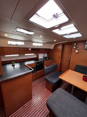 A compact kitchen with a central island, overhead skylights, and a dining area with a bench. - Sun-Kissed Sailing Adventure in Zadar, Croatia (Bibinje)