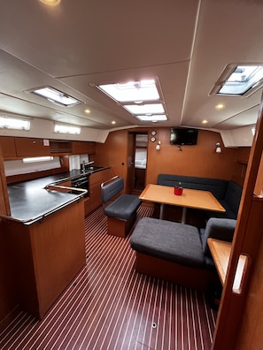 A compact galley with a sink, stove, and a small dining area with a table and benches. - Sun-Kissed Sailing Adventure in Zadar, Croatia (Bibinje)