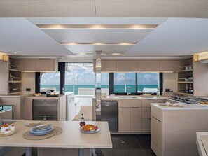 Eine moderne Küche mit Meerblick, ausgestattet mit einer Essecke, einem Tisch für zwei Personen, einem Kühlschrank und einem Herd.