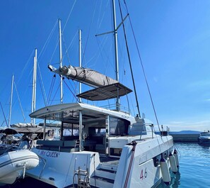 Un velero amarrado en un puerto deportivo, con una cubierta techada, camarote con ventanas y el número '4.6' visible en el costado.