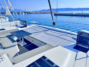 A boat deck with seating, a table, and a view of the water and distant mountains.
