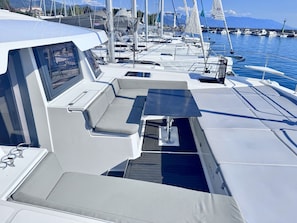 A boat deck with seating areas and a view of other boats in the marina.