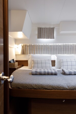 A neatly arranged bed with pillows, a bedside lamp, and a small bedside table with a book and a basket.
