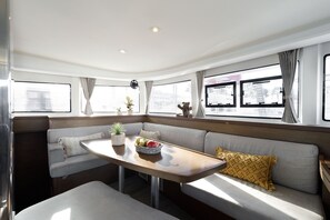 A cozy RV interior with a dining table, seating area, and large windows.
