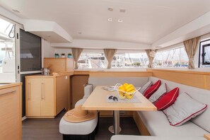 A compact galley with a dining table, cushioned seating, and a small kitchenette.