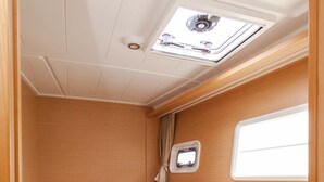 Interior compacto e bem iluminado, com uma cama, uma pequena janela e um claraboia.