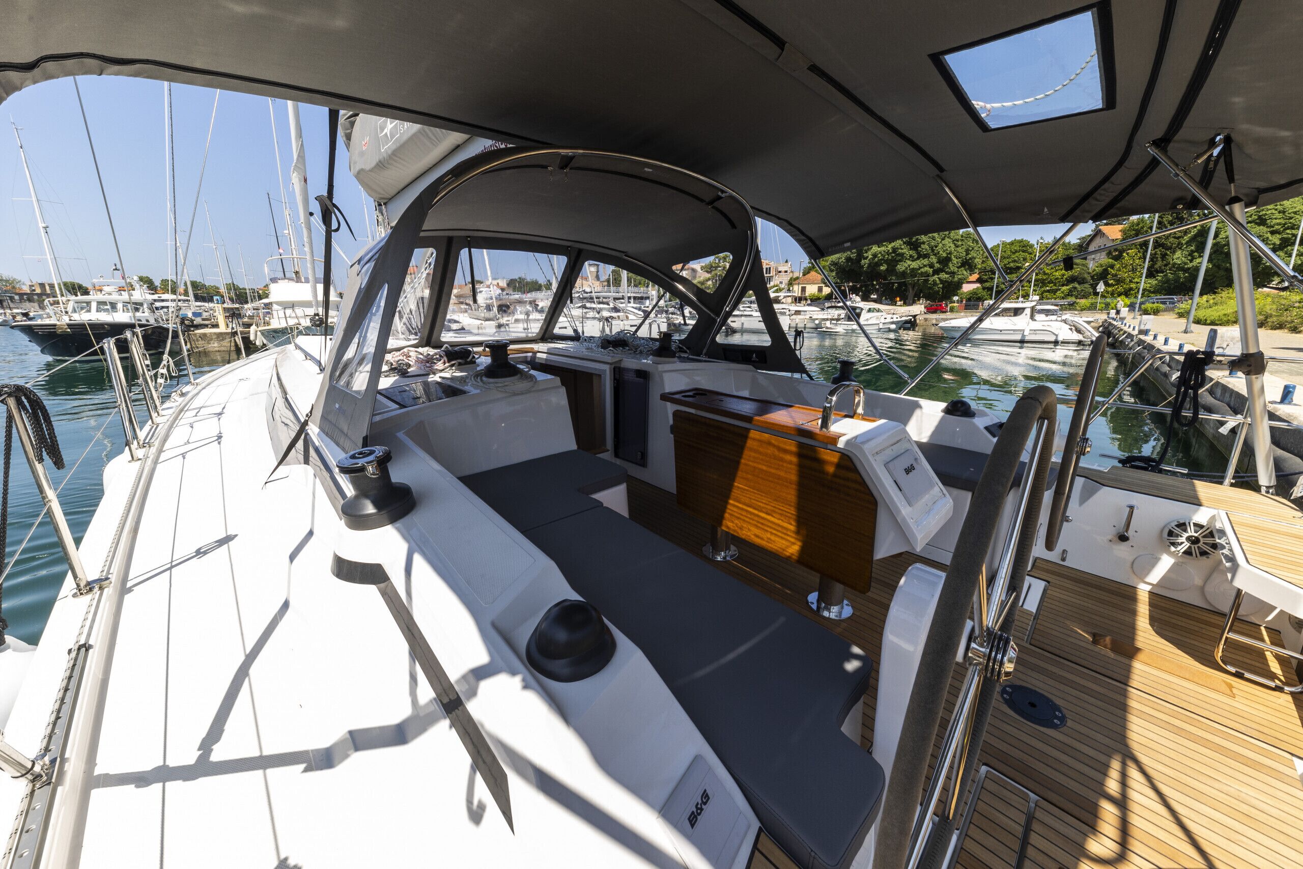 A boat's deck with a seating area, a table, and a view of the marina.