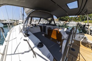 A boat's deck with a seating area, a table, and a view of the marina.