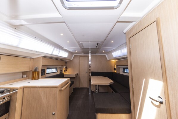 A compact RV interior with a kitchenette, a dining area, and a sleeping berth.