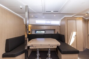 A compact, well-lit interior with a foldable table, cushioned seating, a built-in TV, and a door leading to another room. - Sun-Kissed Sailing Adventure in Zadar, Croatia (Zadar)
