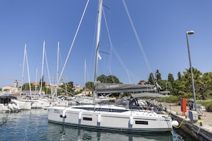 Ein Yachthafen mit mehreren Segelbooten, einer überdachten Fläche und einem Gebäude im Hintergrund.